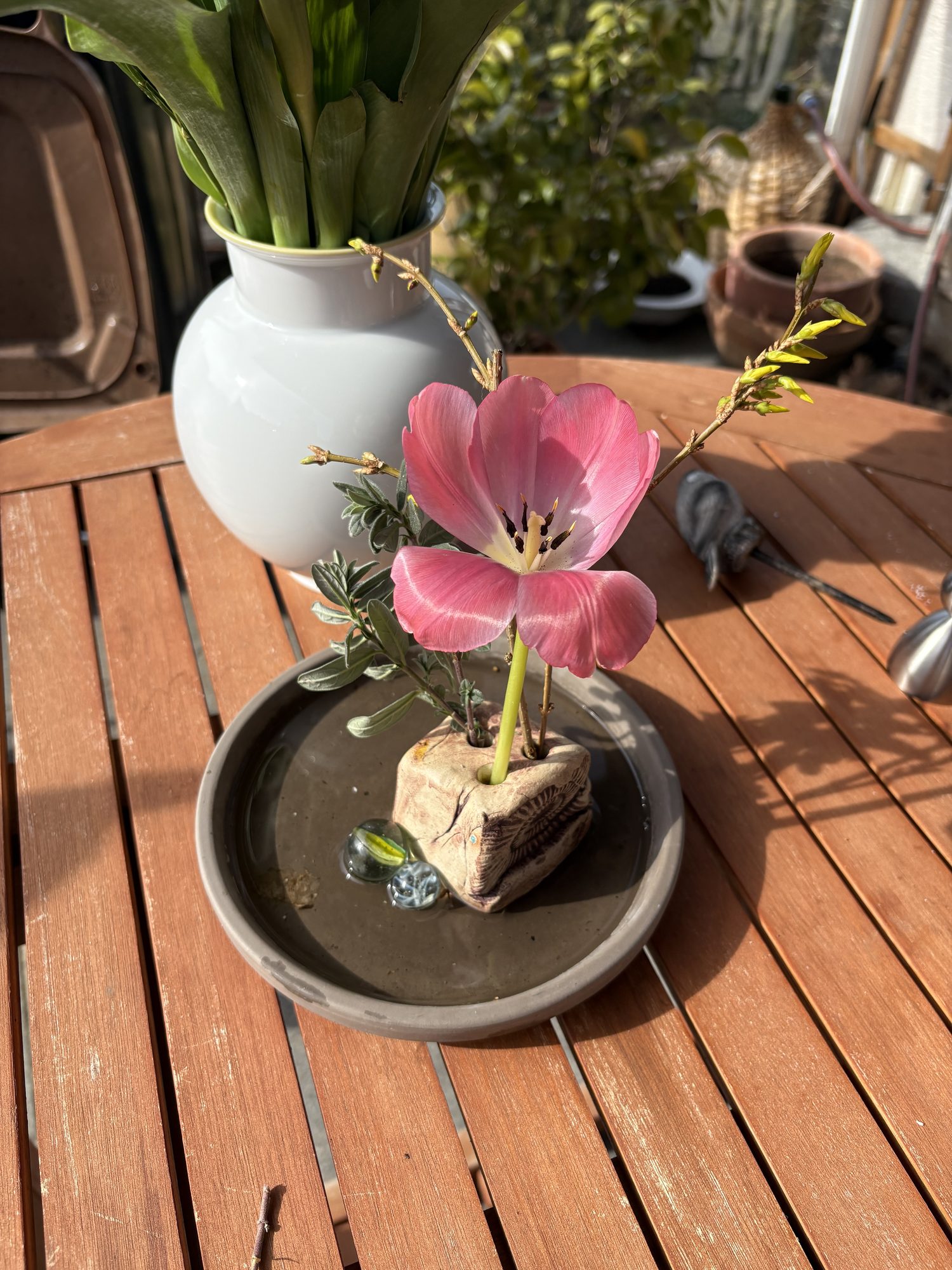 Handcrafted ceramic vase with pink tulips on a sunny wooden table